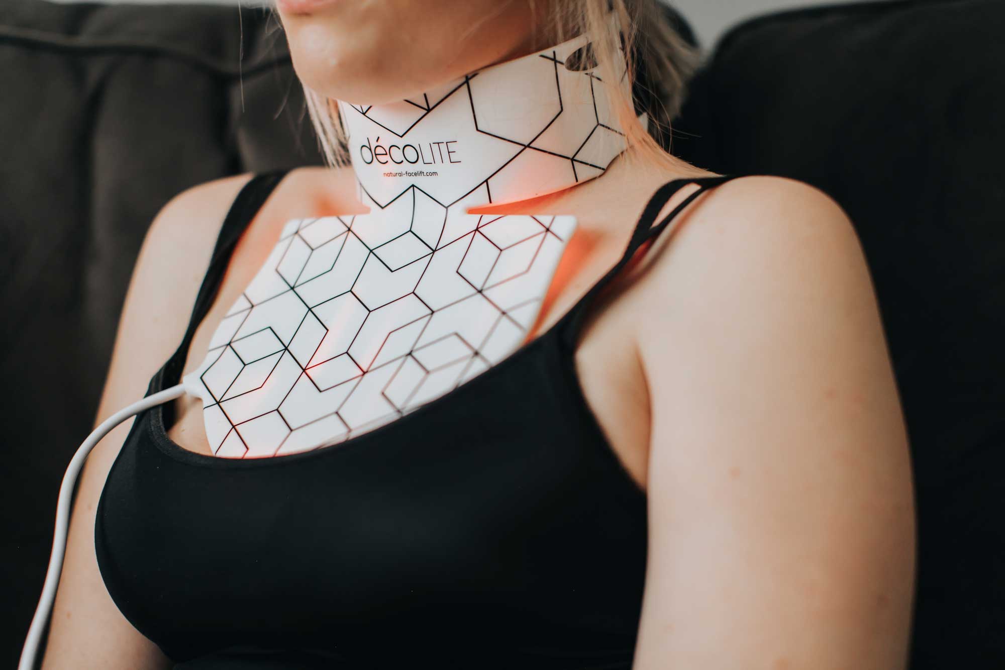 Model using Décolite LED mask for neck and chest light therapy