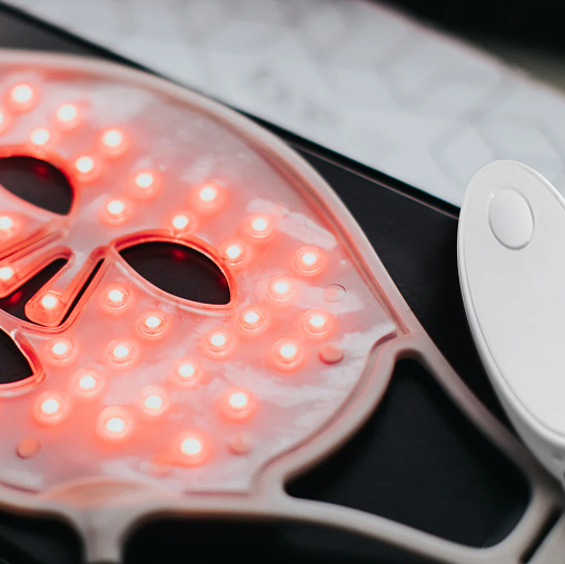 Red light therapy mask device shown close-up with illuminated LEDs