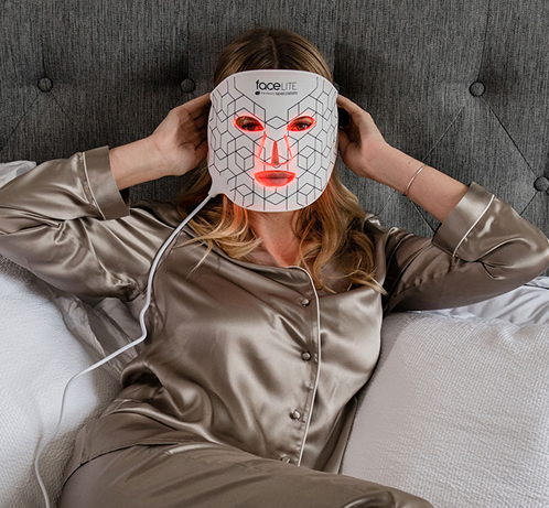 Relaxed woman wearing FaceLite LED mask while lying in bed