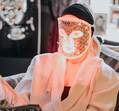 Person wearing FaceLite LED mask in a home setting